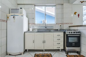Una cocina equipada con refrigerador, microondas, horno y ventana con vista a un edificio.