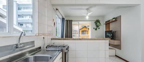 Een moderne keuken met een roestvrijstalen spoelbak, een gasfornuis en een plafondventilator.