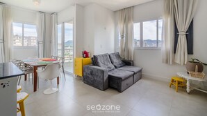 A modern living room with a grey sofa, a yellow side table, and a dining area with a white table and chairs. - Charm and Comfort 600m From the Beach! Etpa1103 (Porto Belo)