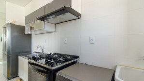 A modern kitchen with a built-in gas stove, stainless steel appliances, and a compact sink. - Charm and Comfort 600m From the Beach! Etpa1103 (Porto Belo)