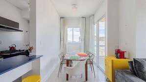 A modern kitchen with a blue countertop, a dining table with chairs, and a yellow cabinet. - Charm and Comfort 600m From the Beach! Etpa1103 (Porto Belo)