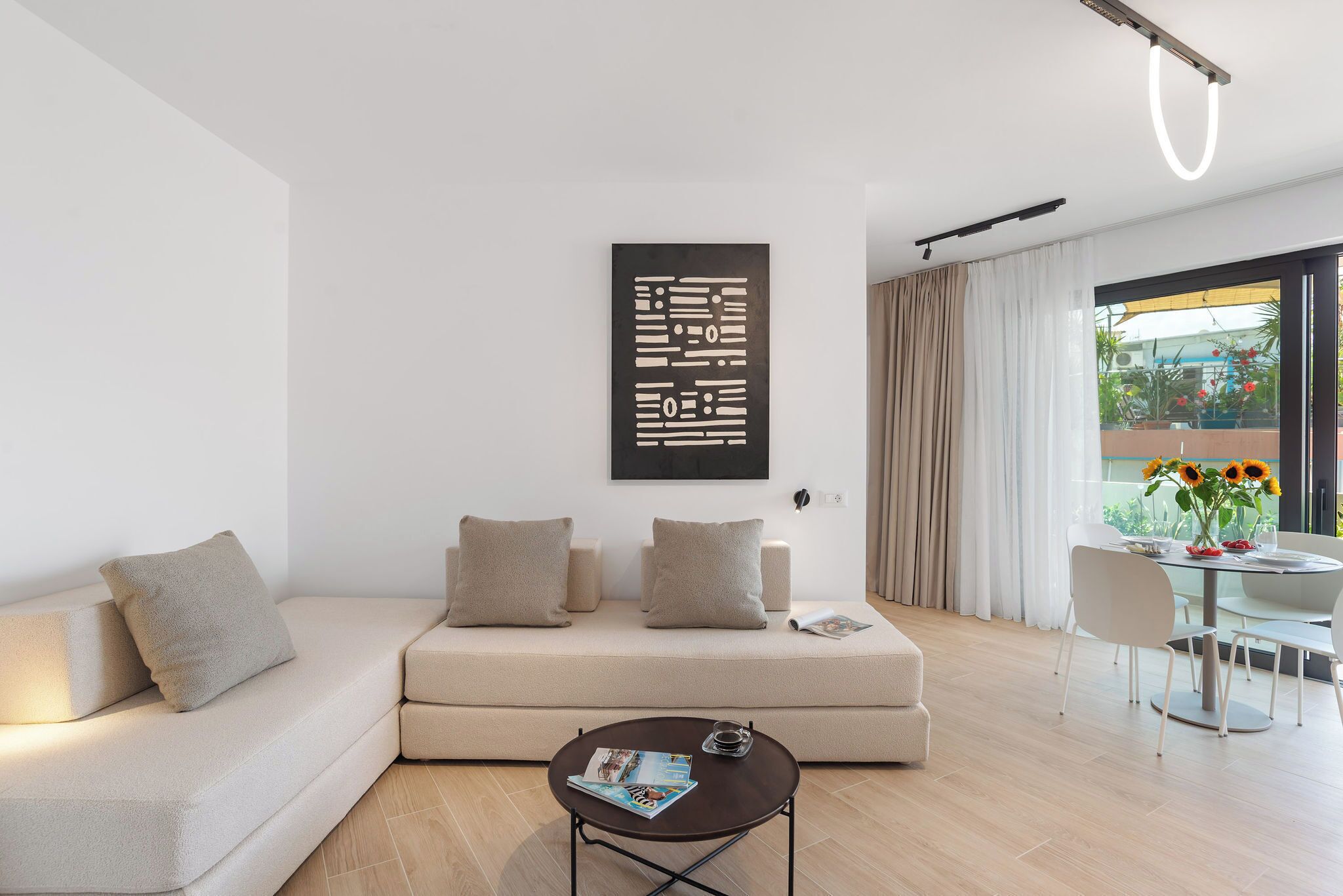 A modern living room with a sofa, a coffee table, and a dining area with a table and chairs.