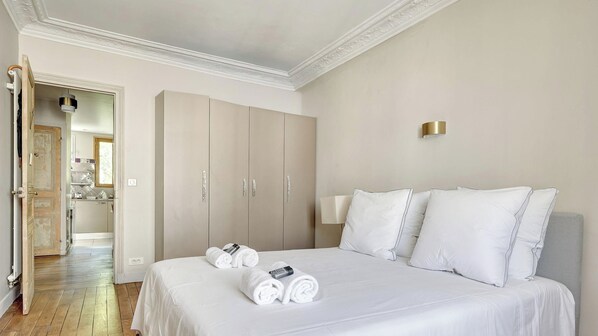 A hotel room with a bed, two pillows, a bedside lamp, a wardrobe, and a bathroom visible through an open door.