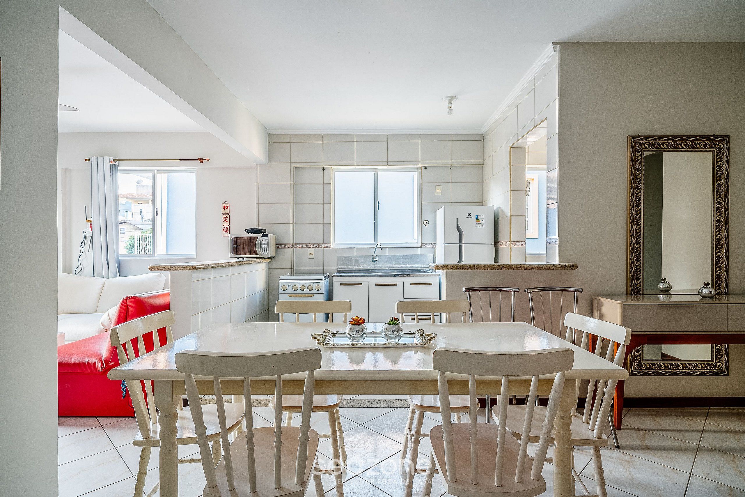 A modern kitchen with white cabinets, a dining table with chairs, and a large window.