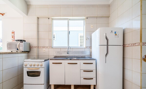 A compact kitchen with a stove, microwave, sink, and refrigerator. - Apt W/barbecue 3 Minutes From Bombas Beach Fdl101 (Bombinhas)