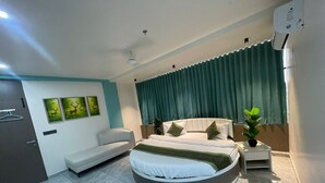 Een moderne slaapkamer met een rond bed, een bank, een nachtkastje en een raam met gordijnen.