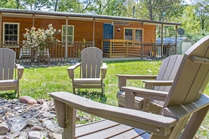 A wooden cabin with a porch, three Adirondack chairs, and a small shed in the background. - Peaceful with Firepit, Hiking & River Access Pet Friendly! (Luray)