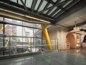 A modern interior with glass railings, a reception desk, and a lift ascensor. - GettSleep Madrid Capsules - Terminal T4S, Departures (Madrid)