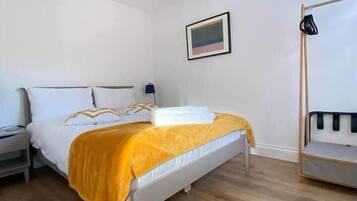 Una camera da letto con un letto, un comodino, una lampada a sospensione, un quadro appeso al muro e una cuccetta addossata alla parete.
