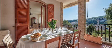 A table set for dining on a terrace with a view of a hillside town.