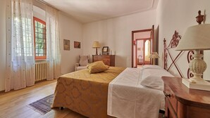 A bedroom with a bed, a dresser, a lamp, and a window with curtains.