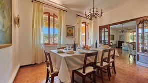 A dining room with a table set for four, a chandelier, and a view of the outside. - Villa Il Masseto, Gaiole in Chianti, Siena and Chianti (Gaiole in Chianti)