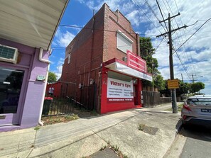 A gym with a red and white sign, a brick building, and a fenced area. - Spacious Studio in Quiet Northcote Neighbourhood (Northcote)