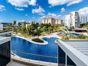 A resort with a large swimming pool, palm trees, and a water slide.