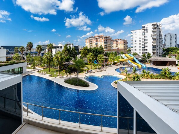 A resort with a large swimming pool, palm trees, and a water slide.