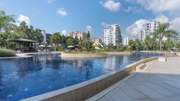 Una piscina techada, una piscina al aire libre, sombrillas