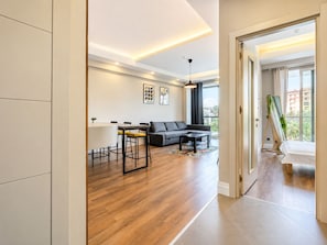 A modern living room with a sofa, coffee table, and dining area.