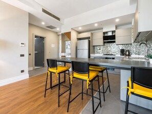 Cozinha moderna com ilha central, banquetas e mesa de jantar.