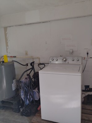 A room with a white washing machine, a large water heater, and a gas cylinder. There are signs on the wall instructing to shake out towels before washing. - Luxury Siesta Key townhome close to village,beaches, city and airport (Siesta Key)