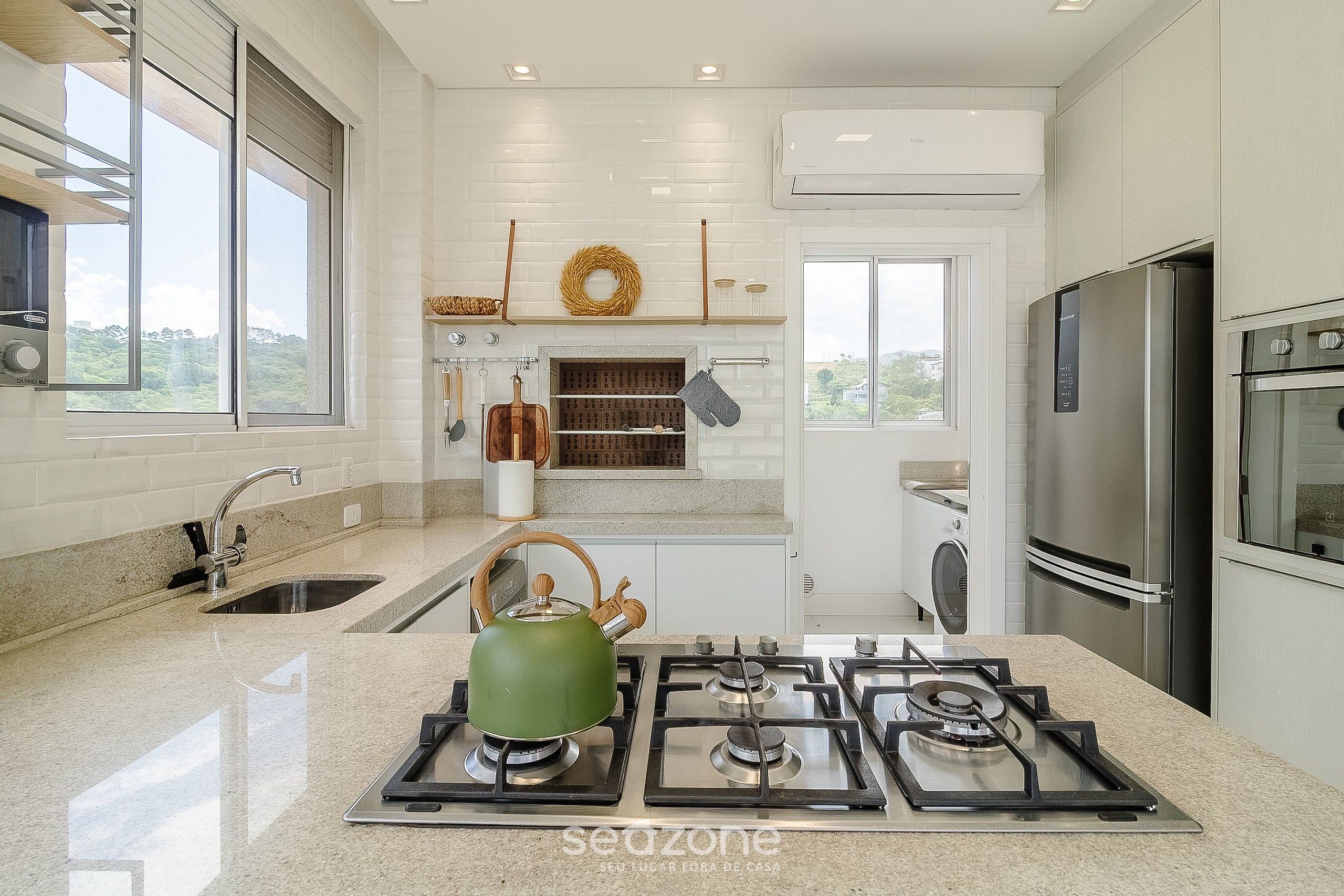 Cocina moderna con estufa a gas, electrodomésticos de acero inoxidable y vistas al exterior.