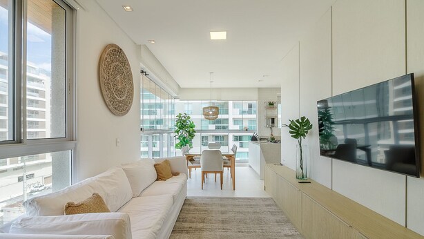 A modern living room with a sofa, a dining area, and a TV mounted on the wall. - Apartment w/ Barbecue 240m From the Beach Ehi0401 (Itajai)