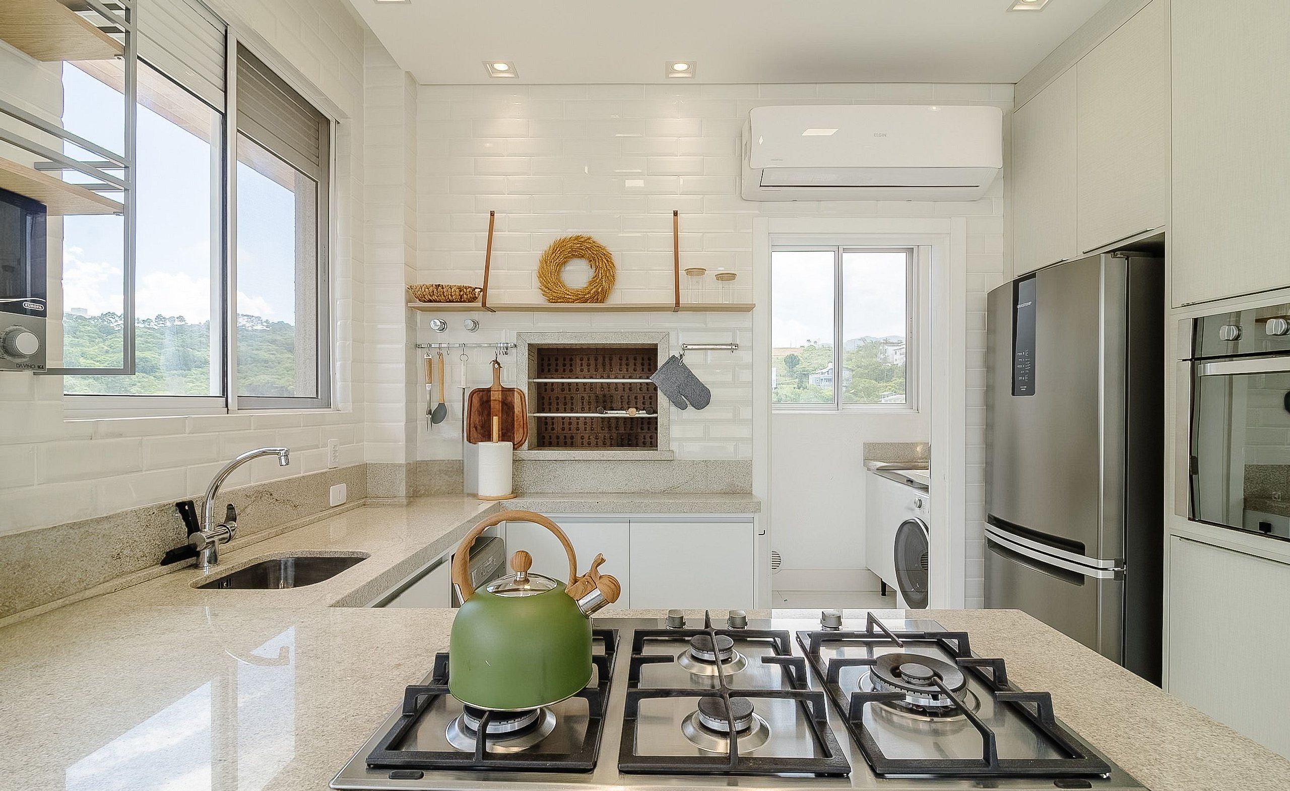 A modern kitchen with a gas stove, stainless steel appliances, and a view of greenery outside.