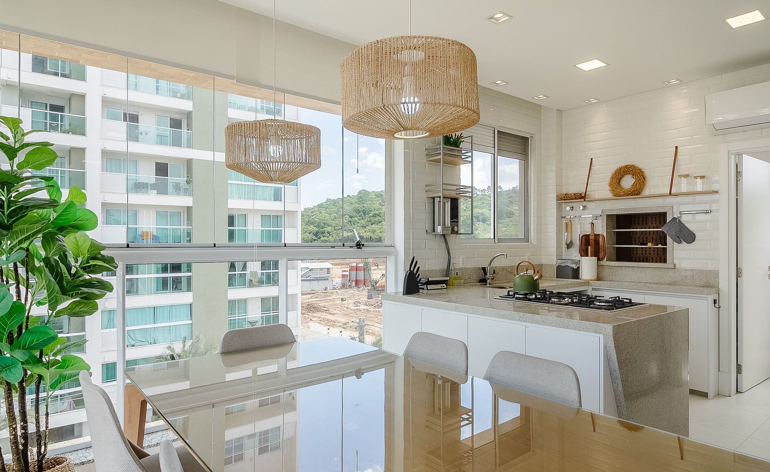 A modern kitchen with a large island, white cabinetry, and a view of a building through large windows.