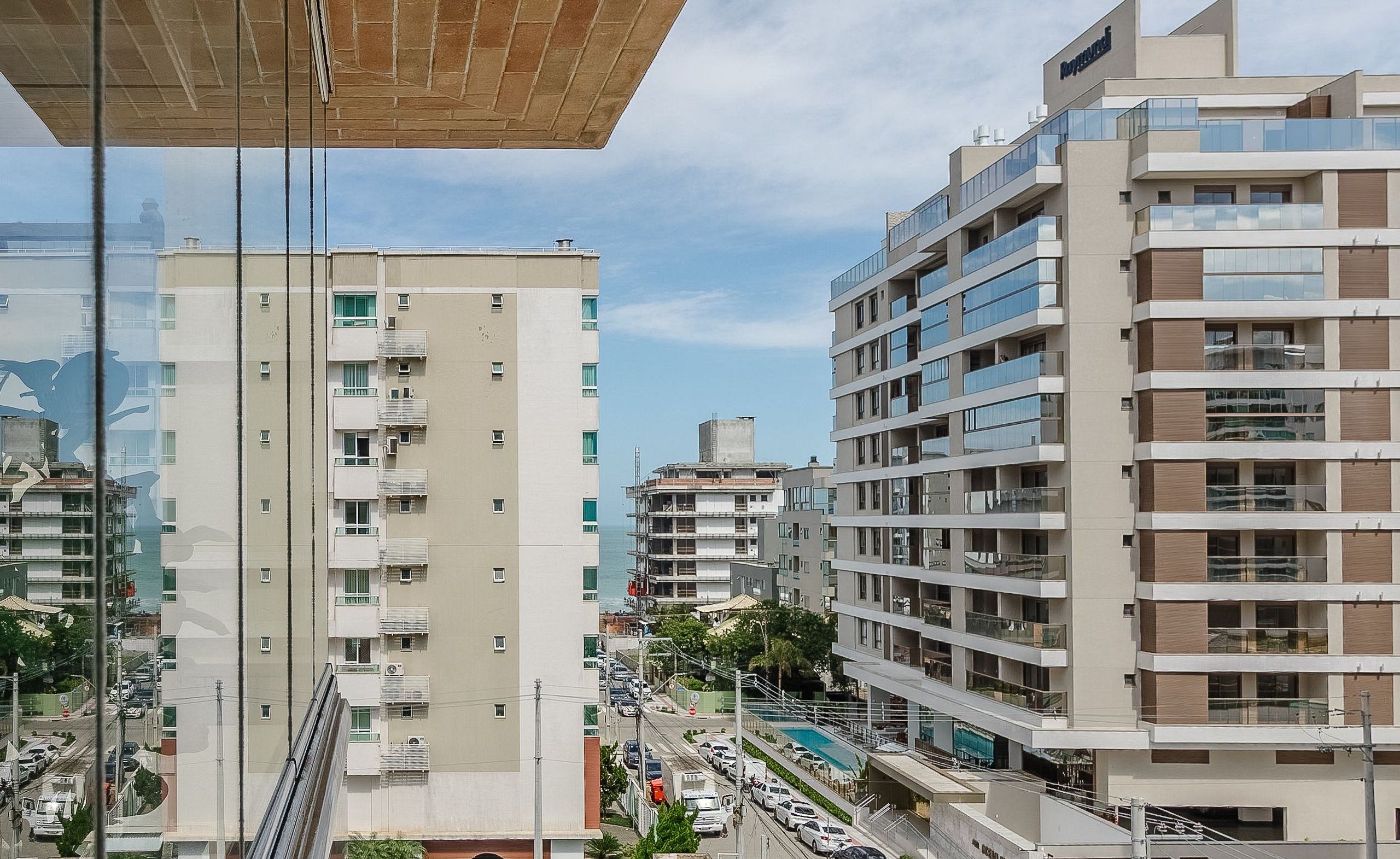 A modern multi-story building with balconies and a street view.