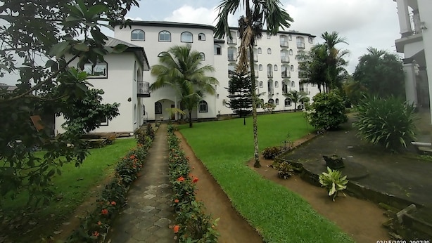 A white building with multiple balconies and a central courtyard with a palm tree. - Jacobs Hôtel (Douala)