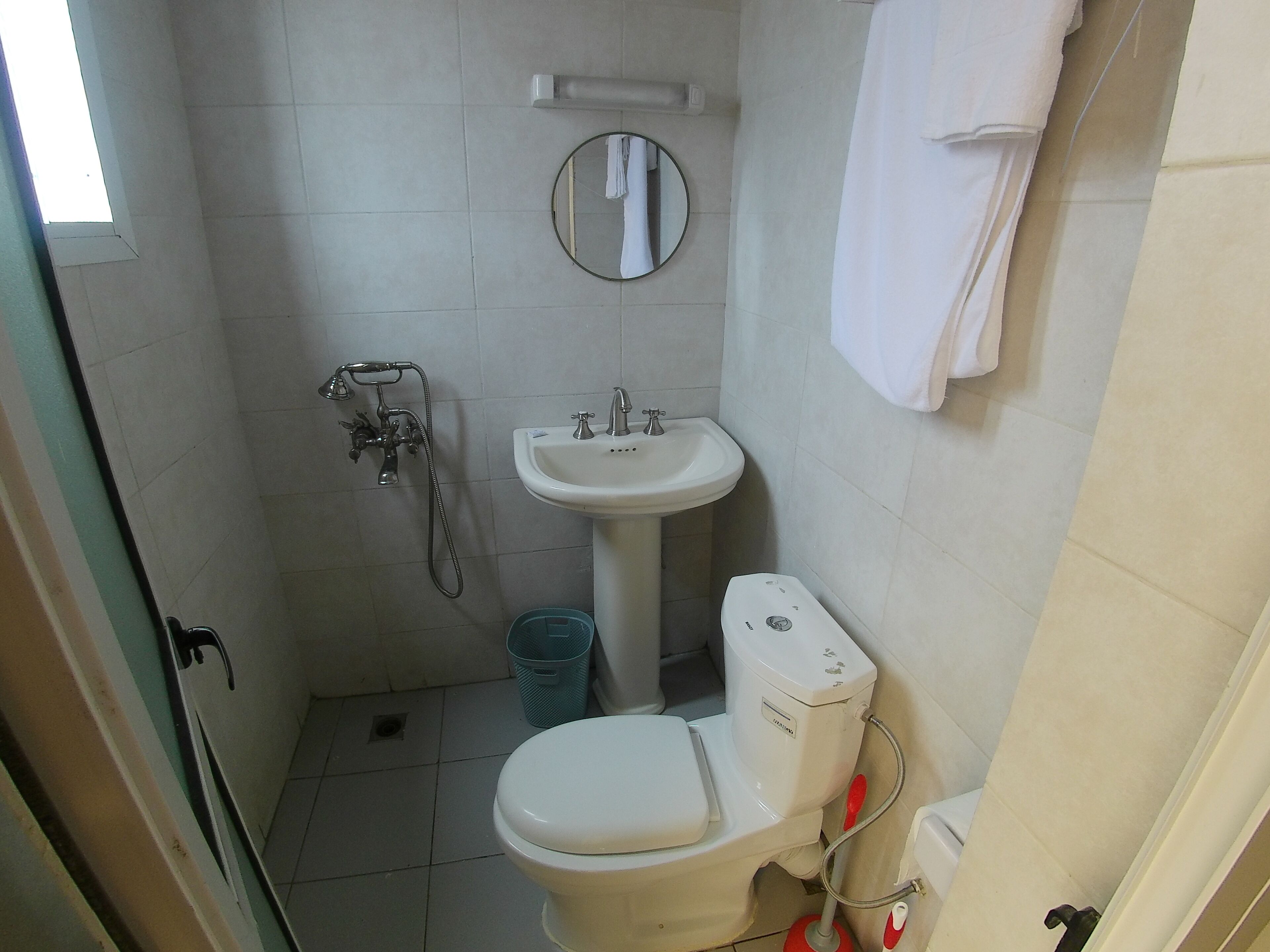 A small, compact bathroom with a toilet, sink, and shower.