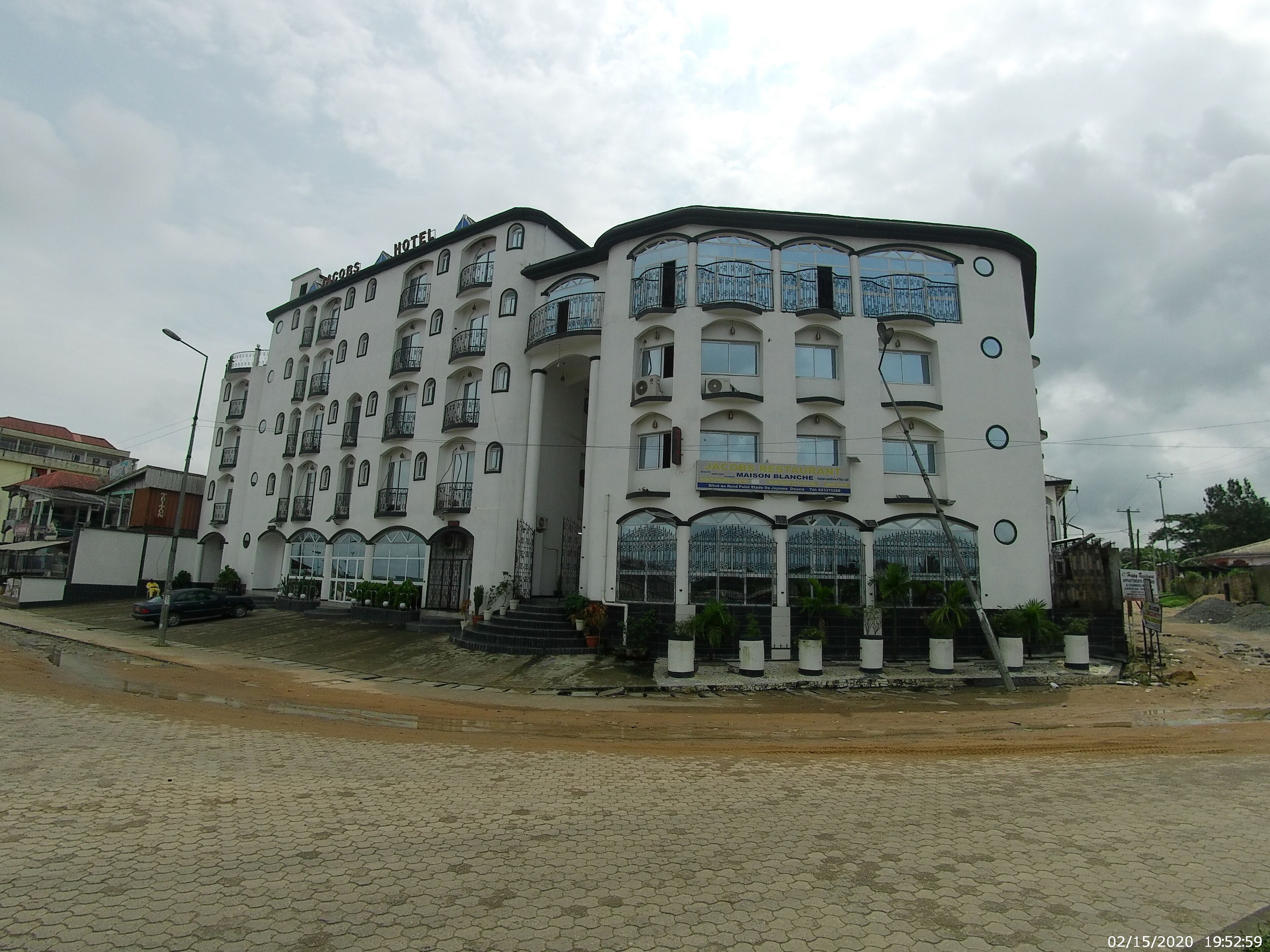 A multi-story hotel with balconies, a prominent entrance, and a sign indicating a restaurant on the ground floor.