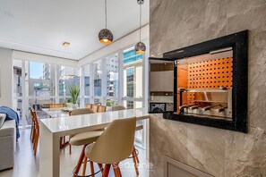 A modern kitchen with a built-in wine rack, large windows, and a dining area with a white table and chairs. - Modern 3BR apt Near the Beach Ema0201 (Itapema)