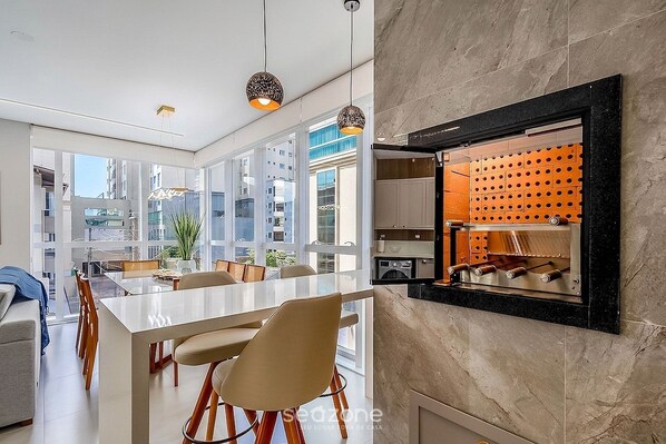 A modern kitchen with a built-in wine rack, large windows, and a dining area with a white table and chairs.