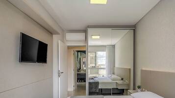 A hotel room with a bed, bedside table, and a television mounted on the wall.