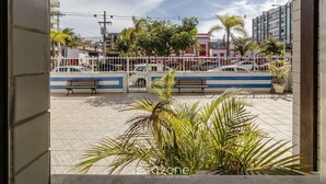 Un espace extérieur doté d’un sol carrelé, de bancs, d’une clôture blanche et de palmiers.