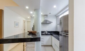 A modern kitchen with a black countertop, white cabinets, and stainless steel appliances.
