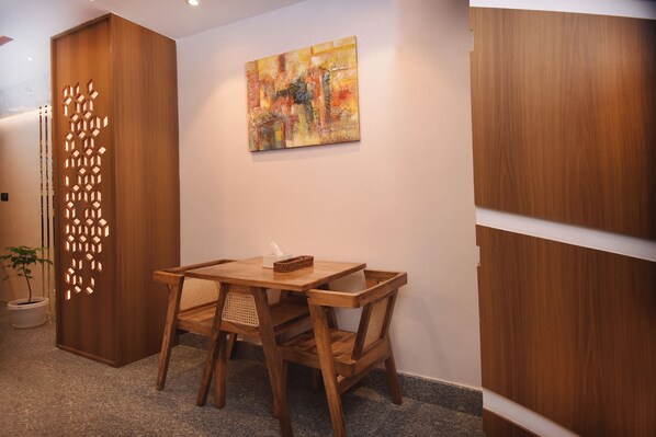 Una mesa de comedor de madera con sillas, un cuadro en la pared y un panel decorativo de madera con diseños recortados.