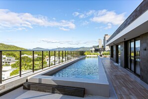 En pool på taket med utsikt över berg och grönområden.