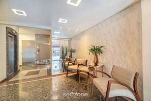 A hotel lobby with a marble floor, a reception desk, seating area, and a patterned wall. - Sea View Apt, Priv. Loc. 2min fr th sea BC Esa0902 (Balneário Camboriú)