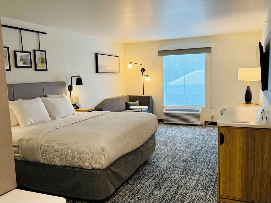 Habitación de hotel con cama, escritorio, silla, televisión y ventana con vistas.
