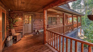 Een vakantiehuisje van hout met een houten veranda, een deur en een bank.
