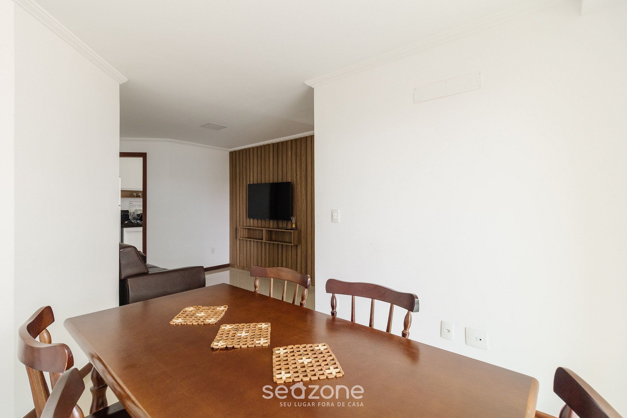Un comedor con una mesa de madera, seis sillas y dos individuales tejidos.