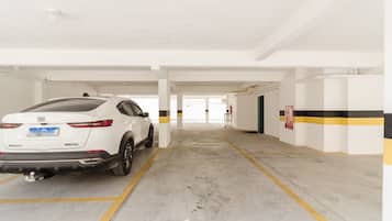 A white SUV parked in a parking garage with white walls and yellow lines.