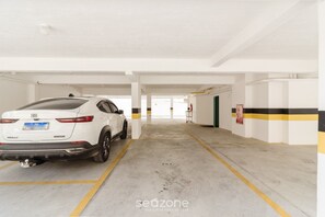 A white SUV parked in a parking garage with white walls and yellow lines.