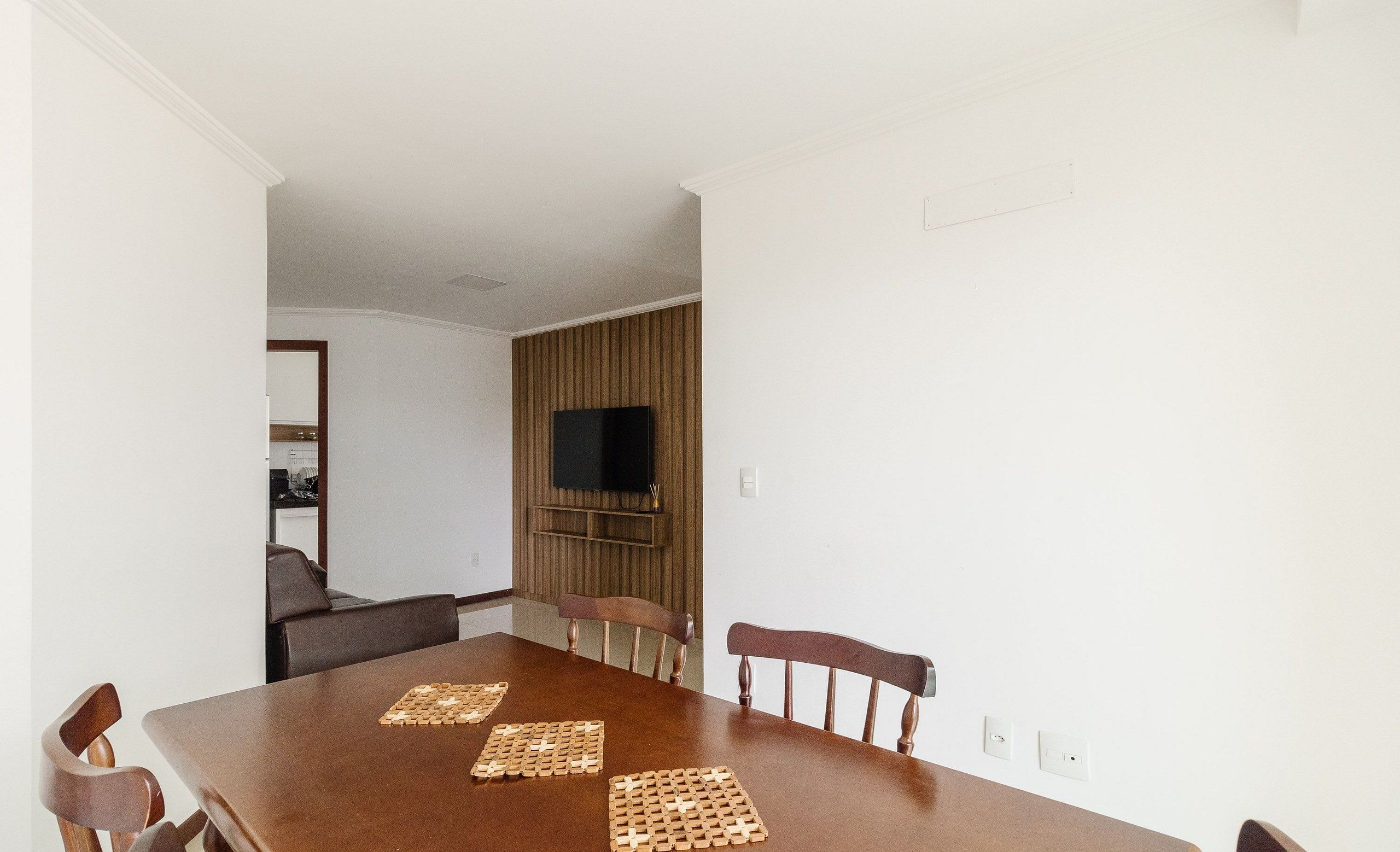 Un comedor con una mesa de madera, seis sillas y dos individuales tejidos.