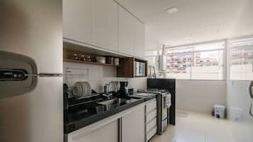 A modern kitchen with white cabinets, a black countertop, and a window with a view of buildings.