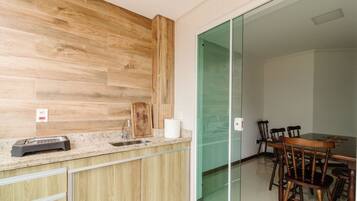 A modern kitchen with wooden cabinetry, a built-in stove, and a dining area with a glass partition.