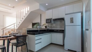 Cocina moderna con armarios blancos, encimera negra y horno microondas integrado.