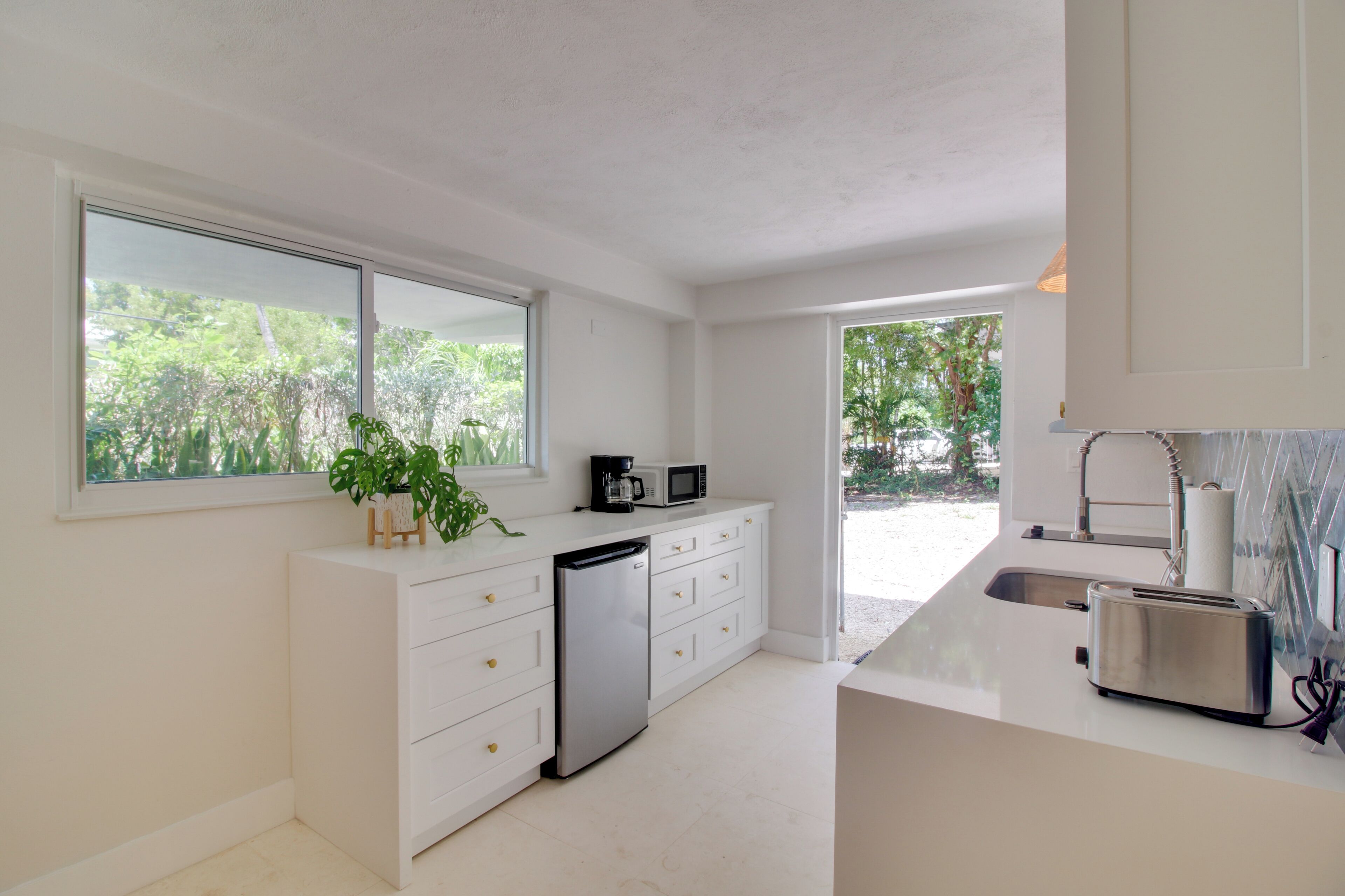 A modern kitchen with white cabinetry, a dishwasher, a coffee maker, and a toaster.