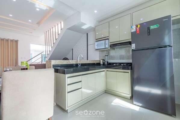 A modern kitchen with stainless steel appliances, a built-in microwave, and a refrigerator. - Beautiful Apt 400m Taperapua Beach, Bahia Edt0009 (Porto Seguro)
